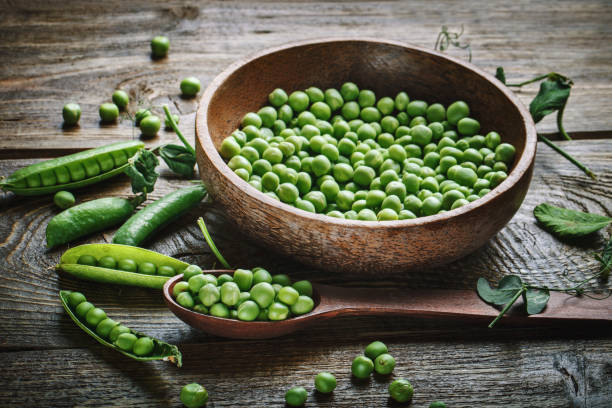 istock Delicious ripe green peas lying on a wooden table 697834302