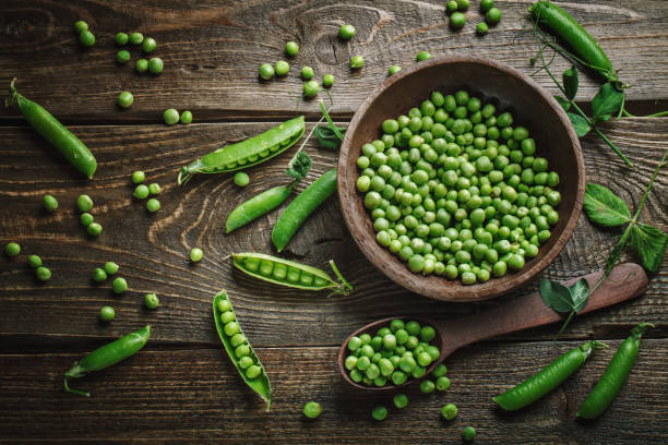 istock Delicious ripe green peas lying on a wooden table 697834342