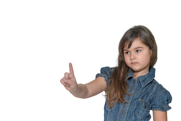 istock Little girl with a serious expression on her face is pointing index finger into space upwards 697839562