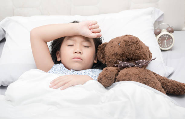 istock kid girl sleeping and sick on the bed with bear doll 697849890