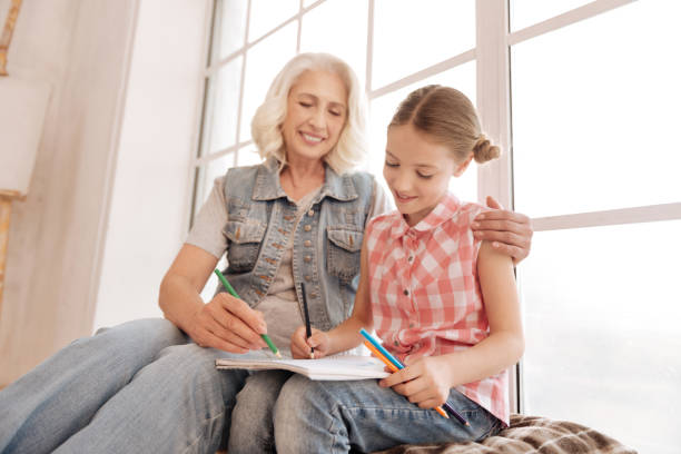 istock Joyful elderly woman drawing with her granddaughter 697850428