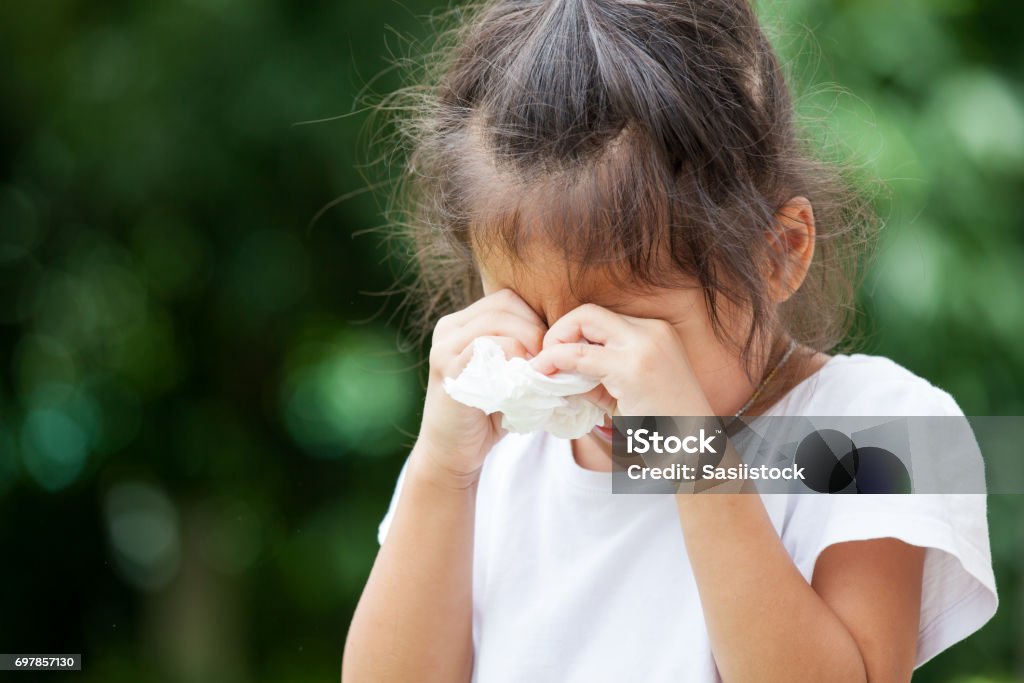 Sad little asian girl crying and holding tissue on her hand Crying Stock Photo