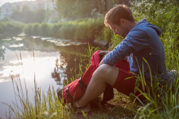 istock Young man sitting next to river and enjoying in sunny day. 697859338