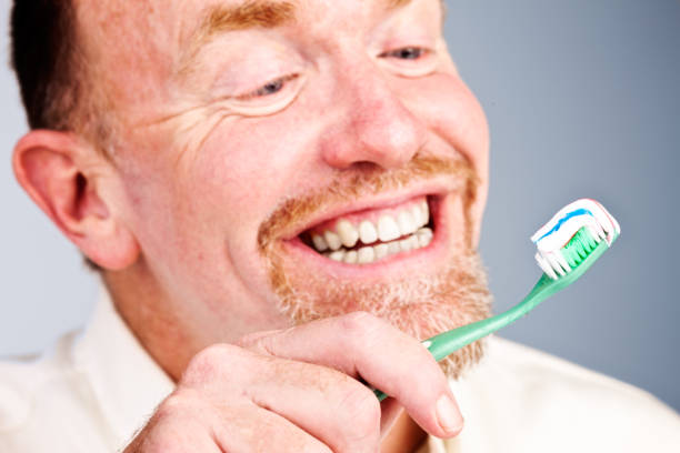 istock Bearded man looks at his loaded toothbrush, smiling 697859412