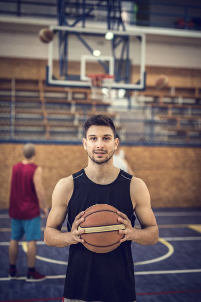 istock Young basketball player holding a ball and looking at the camera. 697860280