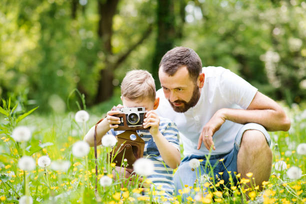 istock Young father with little boy with camera in summer park. 697863202