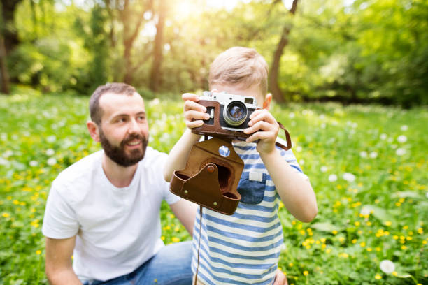 istock Young father with little boy with camera in summer park. 697863286