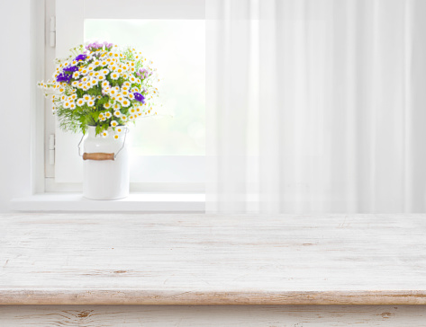 Rustic table in front of wild flowers on wooden window