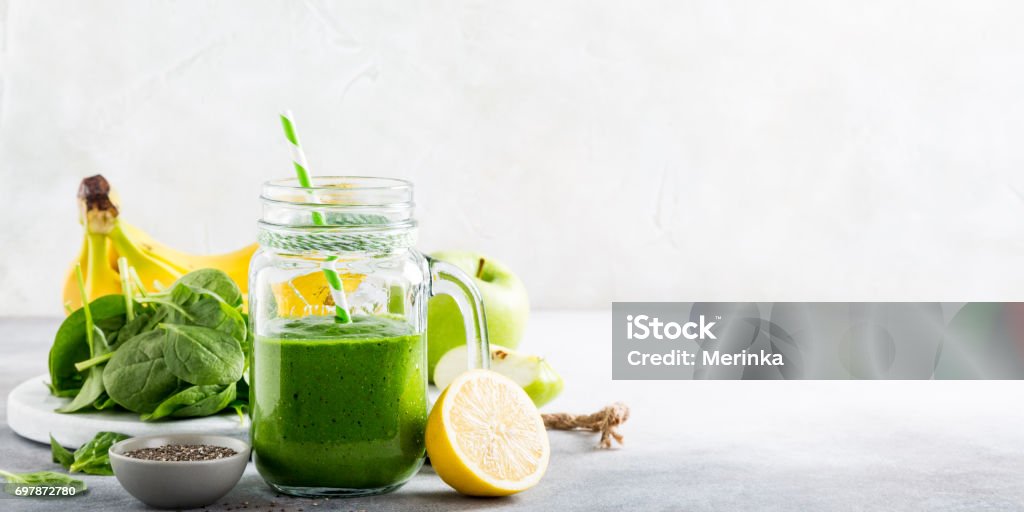 Healthy green smoothie with spinach in glass jar Healthy green smoothie with spinach, banana, lemon, apple and chia seeds in glass jar and ingredients. Detox, diet, healthy, vegetarian food concept with copy space. Smoothie Stock Photo