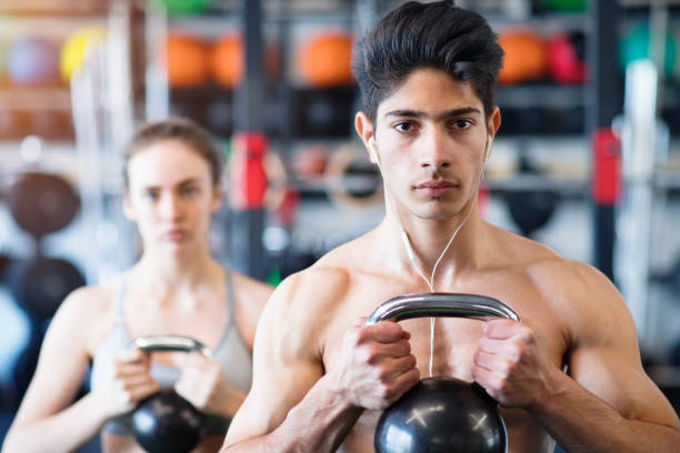 istock Young fit couple in gym exercising with kettlebell. 697883364