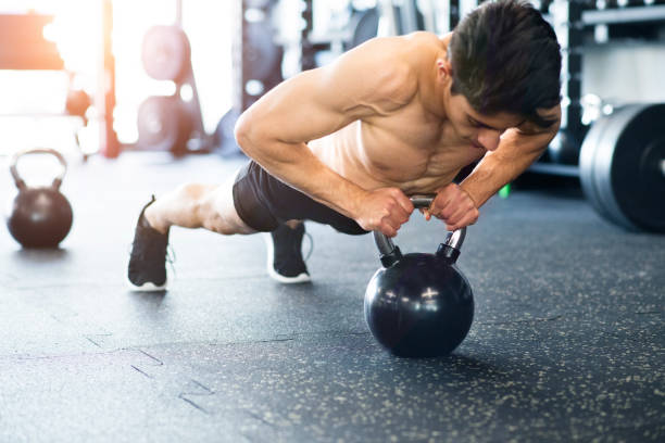istock Young fit hispanic man in gym doing push ups on kettlebell. 697883476