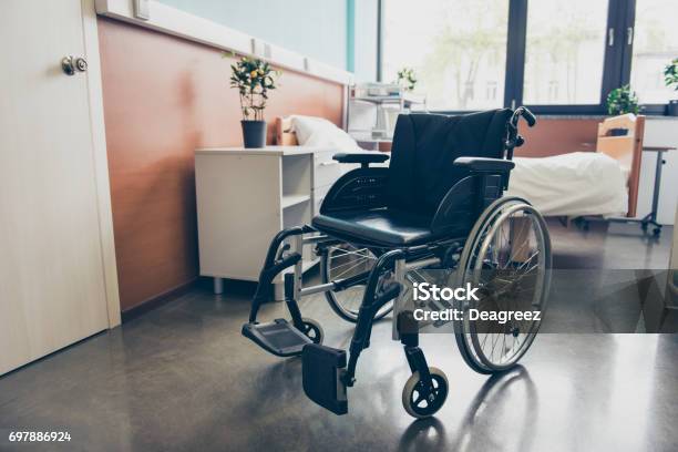 Silla De Ruedas Negro Aislada En La Sala Vacía Del Hospital Foto de stock y más banco de imágenes de Silla de ruedas