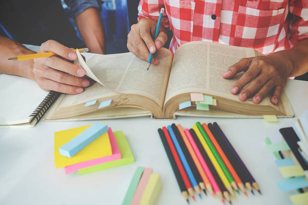 istock Education concept. Students studying and brainstorming campus concept. Close up of students discussing their subject on books textbooks and writing to notebook. Selective focus. 697887328