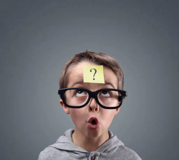 Confused boy thinking with question mark on sticky note on forehead