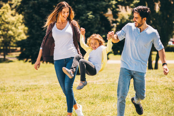 eltern, die ihre tochter in die luft schwingen - parent playful father mother stock-fotos und bilder