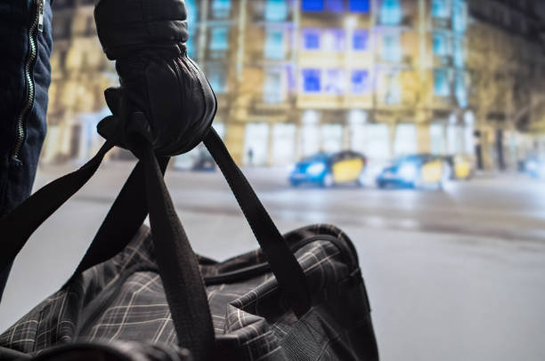 close up of terrorist holding black bomb bag in hand. suicide bomber planning dangerous explosion in city center at night. traffic, cars and buildings in background. terrorism and security concept. - central europe fotos imagens e fotografias de stock