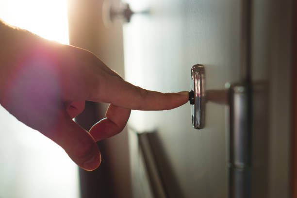 Finger pressing doorbell in sunny apartment building corridor. Close up of male hand ringing door bell in a block of flats. Salesman, fundraiser, guest or visitor behind door. Hand ringing doorbell doorbell photos stock pictures, royalty-free photos & images