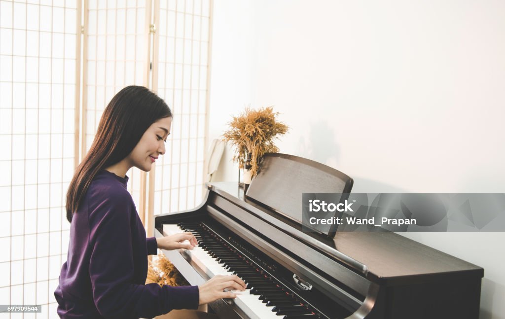 Muy hermosa asiática joven sentado en el piano - Foto de stock de Piano libre de derechos