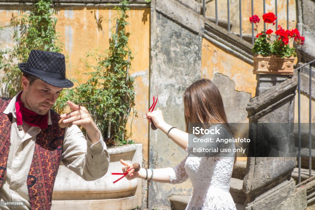 Young Couple Dancing Tarantella in Naples, Italy Naples, Italy - 20 May, 2017: Young couple dancing in the street of Naples the traditional dance called Tarantella, this photo is taken in Spaccanapoli street, in the historical city centre, during the day, the dancers are a young couple wearing traditional dresses. Dancing Stock Photo