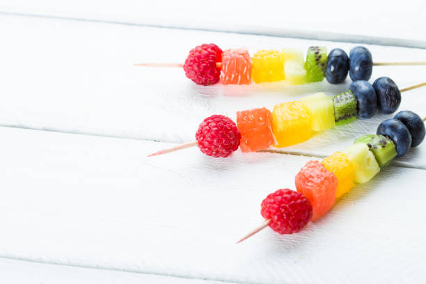 istock Coloerd fruits and berries kebab on wooden table 697913426