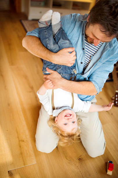 istock Young father at home holding his little son upside down. 697918186