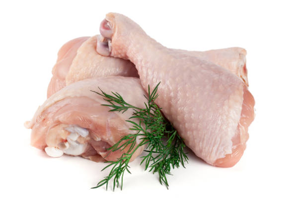 istock Three raw chicken drumsticks with a sprig of dill isolated on white background 697920572