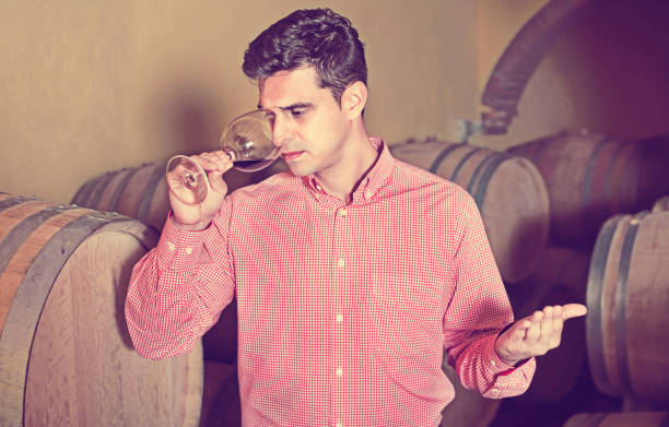 istock Male customer tasting red wine from wooden barrels 697920802