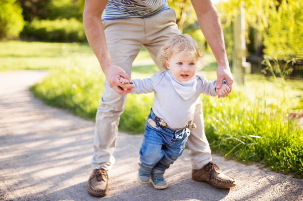 istock Unrecognizable father holding hands of his son taking first steps 697926786