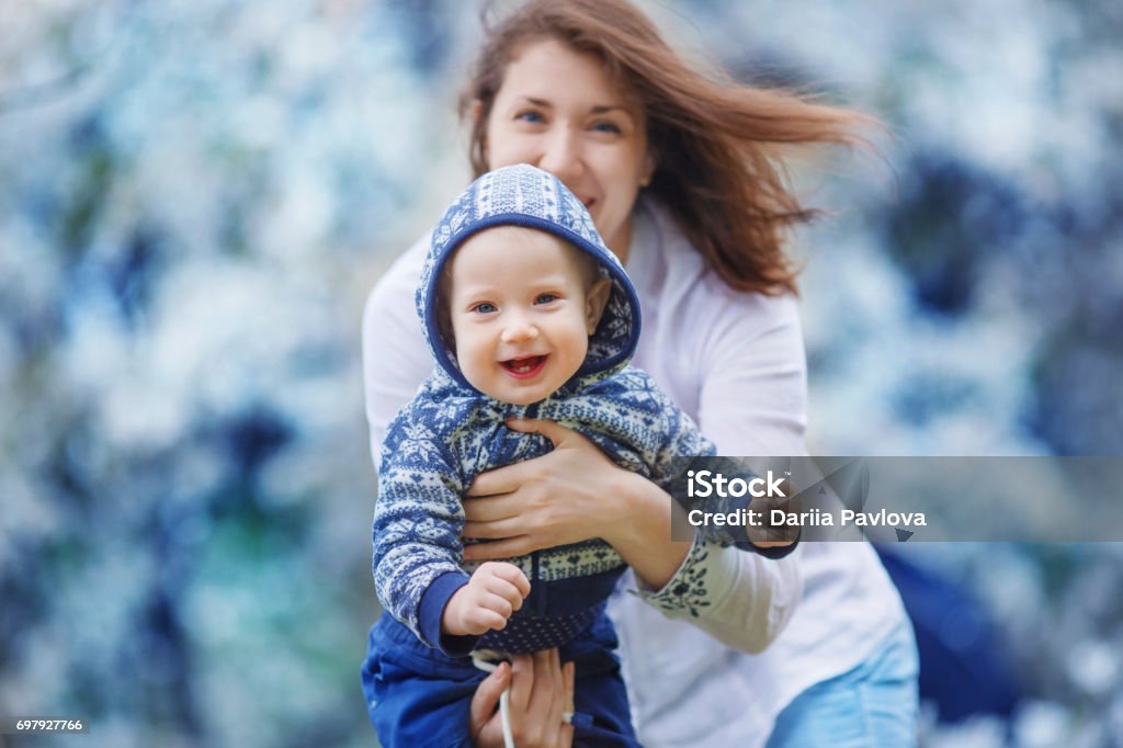 Mother shows the child holding it in her arms A woman shows her six-month baby, holding him in her arms. The kid smiles, wide-open mouth and showing two teeth Animal Behavior Stock Photo