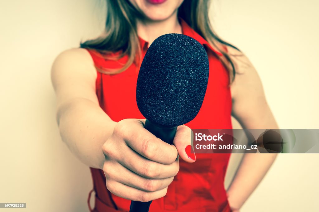 Female reporter with black microphone making interview Female reporter with black microphone making interview - journalism and broadcasting concept Media Interview Stock Photo