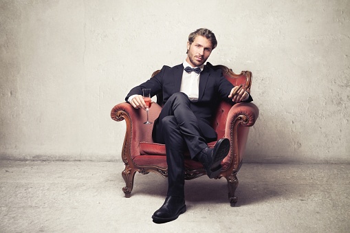 Gentleman in suit is sitting in an armchair