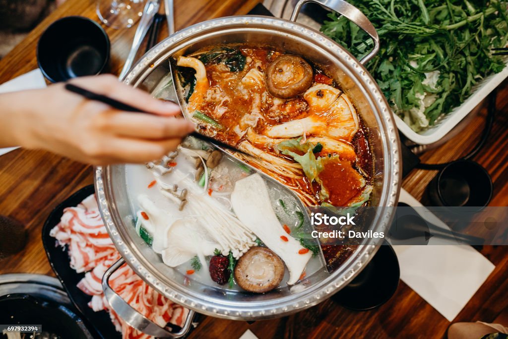 Korean hot pot meal. Hands taking food with chopsticks. Hot pot korean meal in a table. Hot Pot - Dish Stock Photo