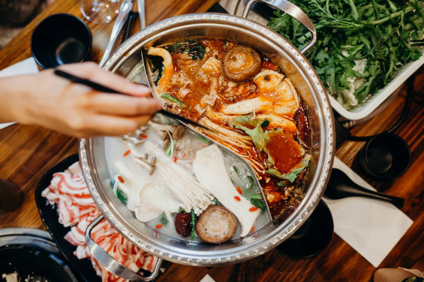 Korean hot pot meal. Hands taking food with chopsticks. Hot pot korean meal in a table. sichuan province stock pictures, royalty-free photos & images