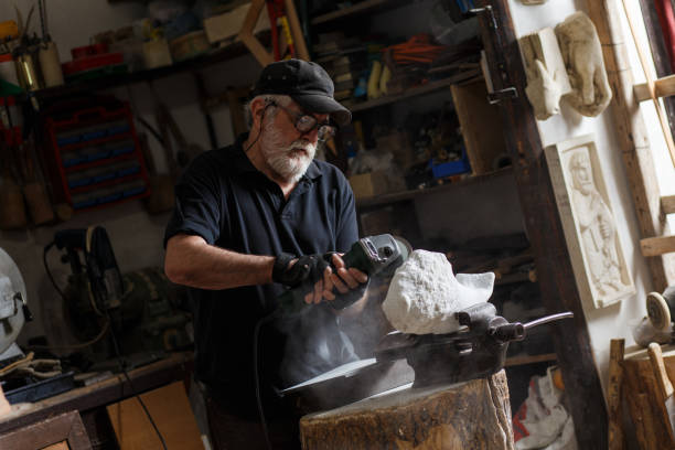 istock Senior sculptor working on his marble sculpture in his workshop with grinder. 697932486