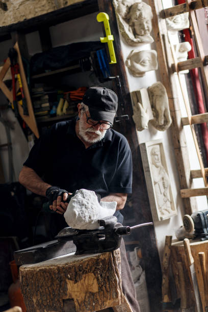 istock Senior sculptor working on his marble sculpture in his workshop with grinder. 697932500