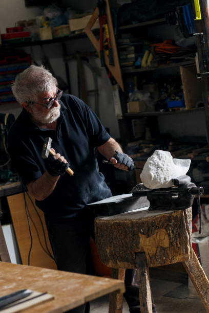 istock Senior sculptor working on his marble sculpture in his workshop with grinder. 697933042