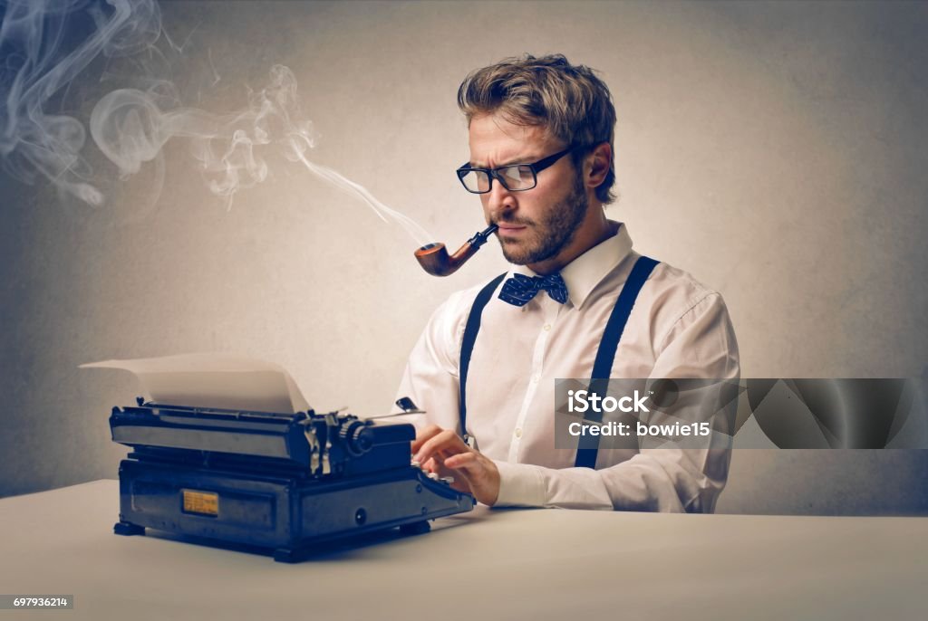 Old styled businessman Old styled businessman is typing with a pipe in his mouth Author Stock Photo