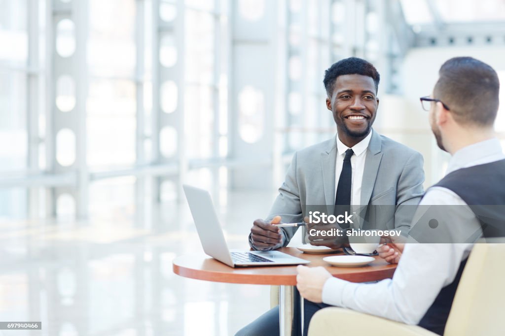 International Business Meeting Portrait of successful African-American businessman smiling during meeting with colleague at coffee break Customer Stock Photo