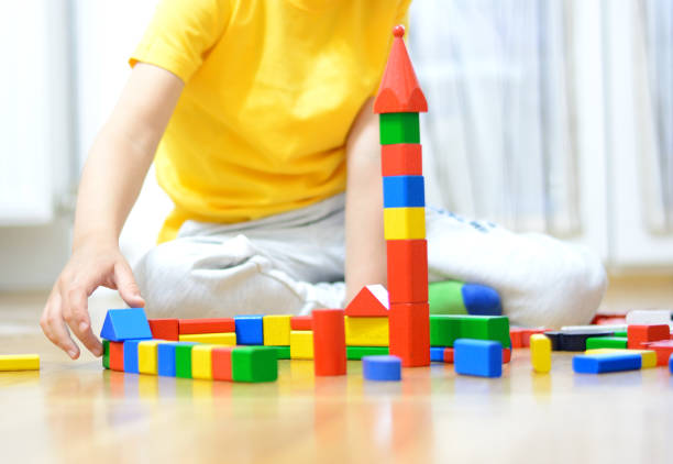 istock Boy is playing on the floor with wooden blocks . 697945656