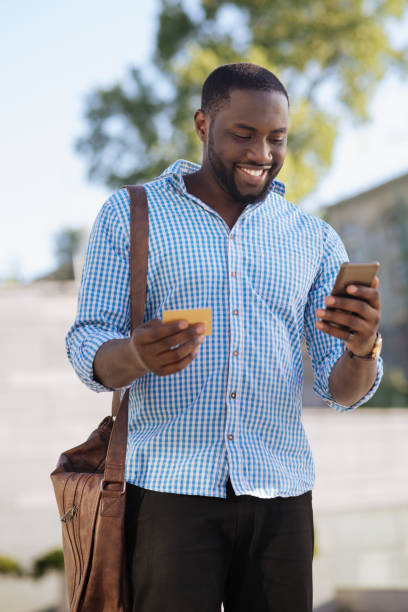 istock Savvy young man using his smartphone for making purchases online 697946600