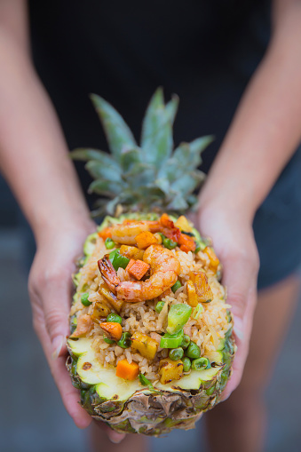 Close up young women holding Thai pineapple fried rice.