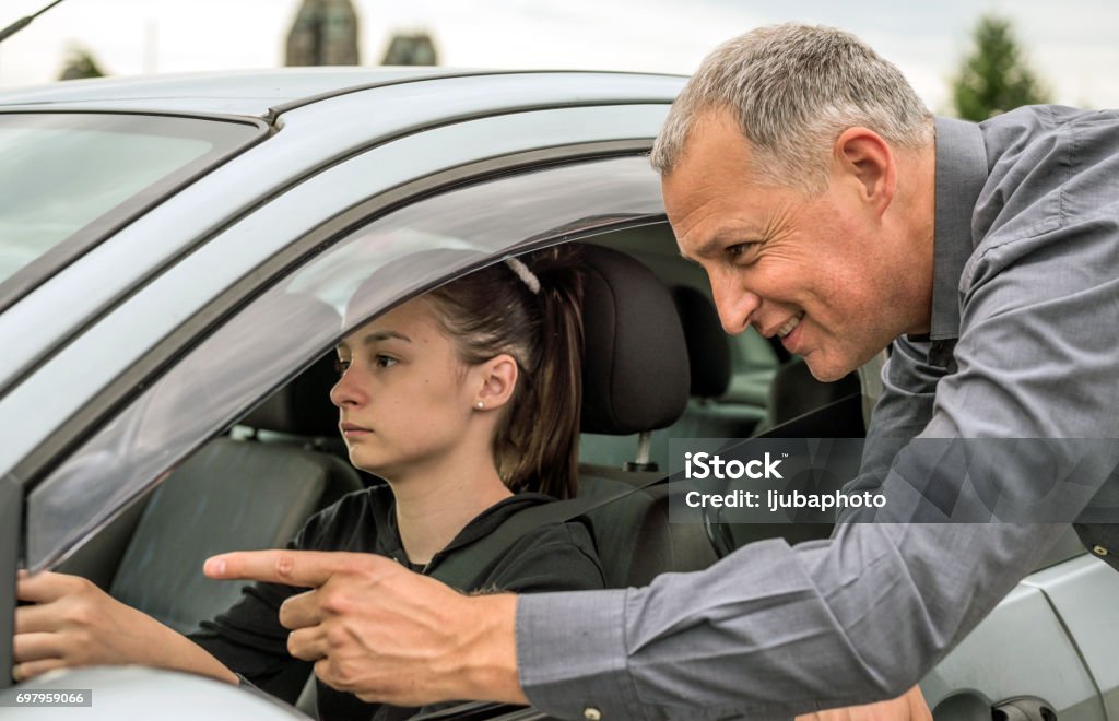 Know where you’re going and get there Father Teaching Teenage Daughter To Drive during bright sunny day. Teen girl taking driving test to get her drivers license. Taking driving lessons from an instructor Driving Stock Photo