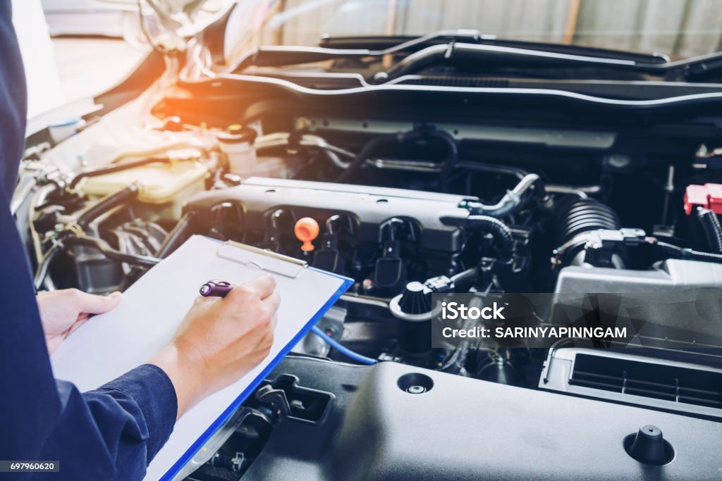 Mechanic man holding clipboard and check the car Auto Repair Shop Stock Photo