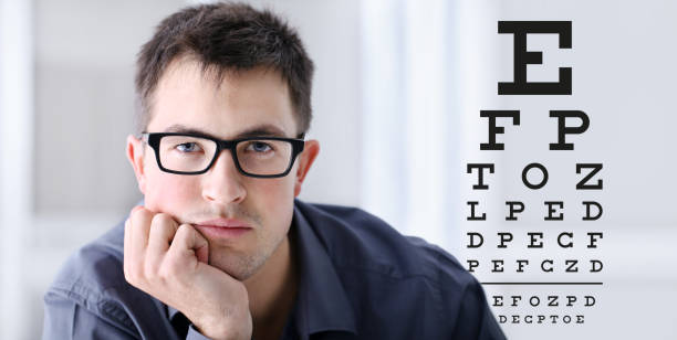 rostro masculino con las gafas de vista prueba fondo gráfico, concepto de oftalmología de la examinación de ojo - doctor reading chart human eye fotografías e imágenes de stock