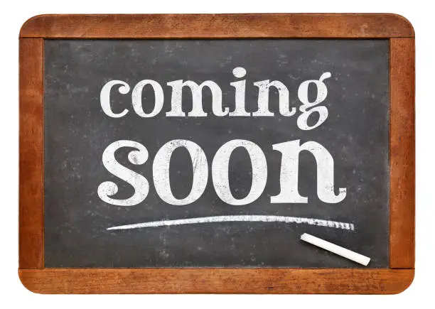 coming soon sign - white chalk text on a vintage slate blackboard