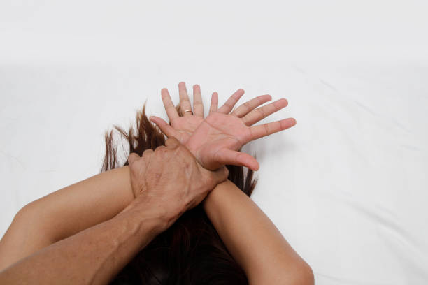 A hairy man's hand holding a woman hand for rape and sexual abuse concept stock photo