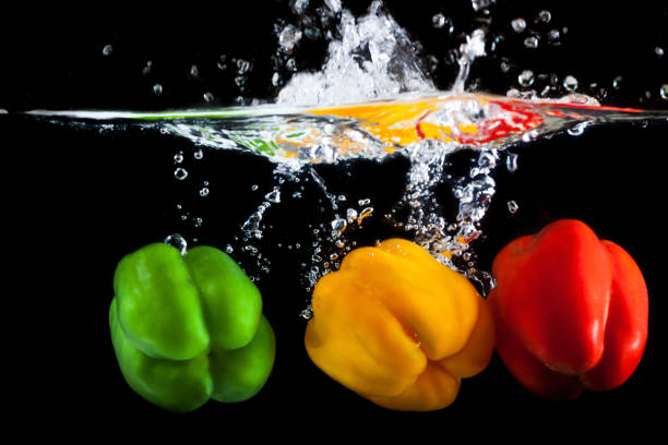 istock Yellow, green and red pepper falling into water 697987186
