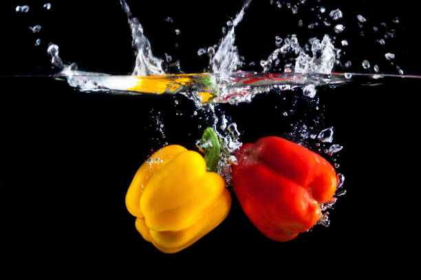 istock Yellow and red pepper falling into water and splashing 697987466