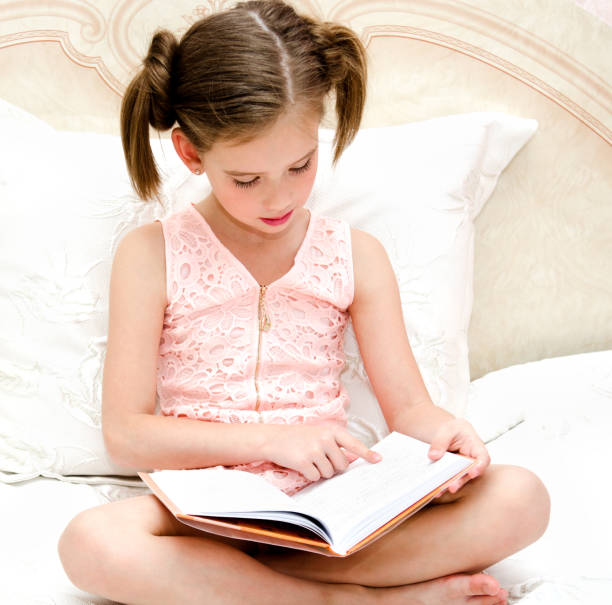 istock Adorable little girl child is reading a book 697998422