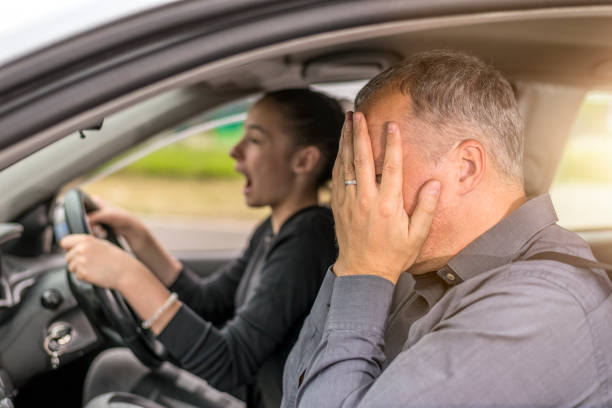 Terrified Father Giving Teenage Daughter Driving Lessons Failed Driving test. Young serious inexperienced woman driving a car in alert, worried instructor man sitting aside and looking nervous at the road, dangerous situation. Fearful driving instructor or father and student. Car accident northern europe family car stock pictures, royalty-free photos & images